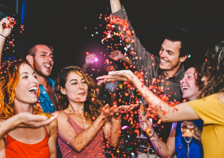 Happy friends doing party throwing confetti in the club